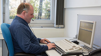 Mann mit Headset vor einem Computer.