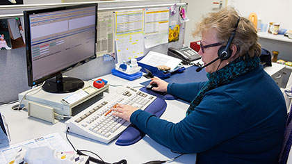 Frau mit Headset arbeitet an einem Computer.