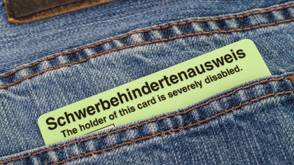 Nahaufnahme: Tasche einer Jeans, aus der eine Ausweiskarte hervorlugt. Sie hat die Aufschrift: „Schwerbehindertenausweis. The holder of this card is severely disabled.“ 