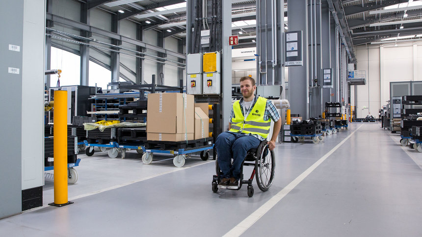 Matthias Neubauer fährt im Rollstuhl durch eine Industriehalle.
