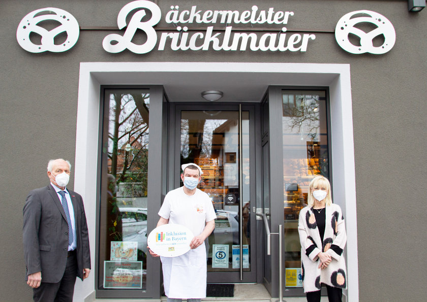 Ein Foto mit Staatsministerin Carolina Trautner sowie den Emblemträgern vor dem Eingang der Bäckerei Brücklmaier