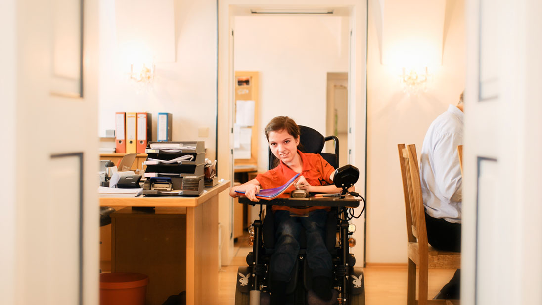 Junge Frau mit Rollstuhl im Büro.