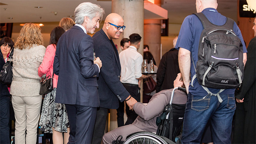 Saliya Kahawatte begrüßt eine Besucherin, die im Rollstuhl sitzt.